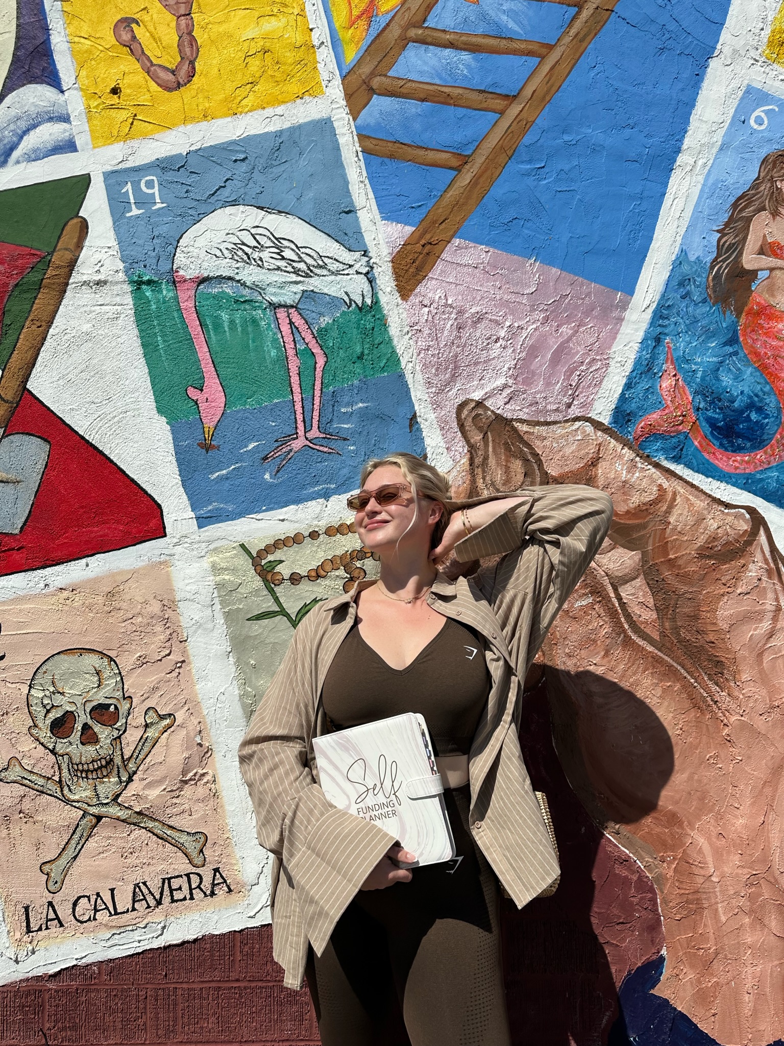 Iskra posing with her Self Funding Planner in front of a mural in Austin.